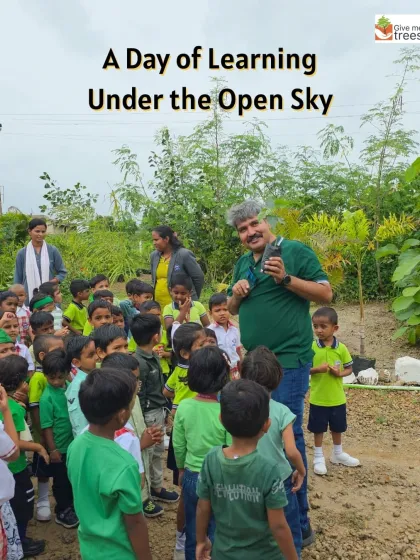 A day of learning under the open sky. An instructor shows a group of young children a sapling up close, sparking their curiosity in a natural setting.