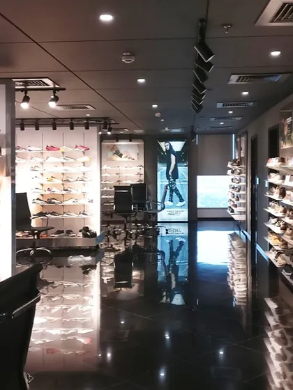 The long view of the Skechers showroom highlights the glossy, reflective flooring and dramatic track lighting. This creates a sleek, modern environment that puts the focus on the products.
