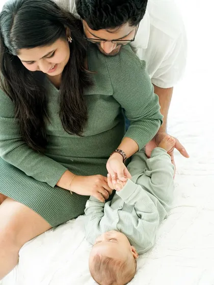 Playful moments with mom and dad. This overhead shot captures a sweet, interactive moment as parents play with their baby's tiny hands.