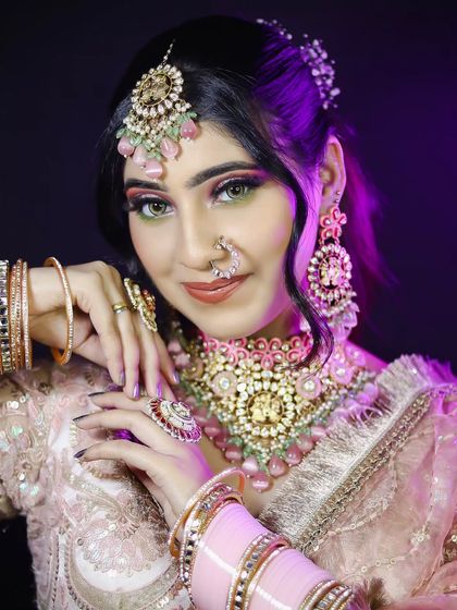 This pose highlights the intricate pink jewelry and the two-toned hair, showing attention to modern bridal trends.