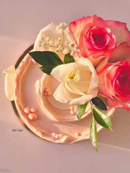 A blush pink buttercream cake adorned with fresh pink and white roses and baby's breath. The soft colors and floral arrangement make it perfect for romantic occasions.