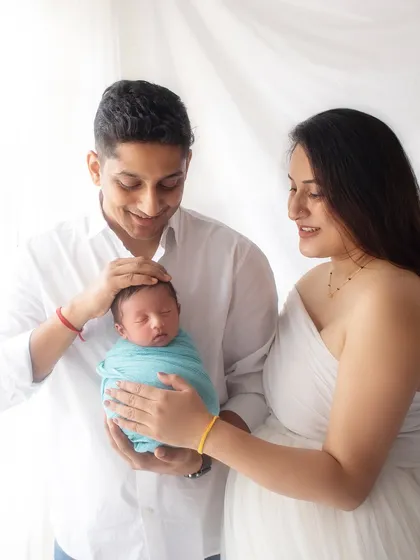A beautiful family of three adoring their new arrival. The simple white outfits and bright background keep the focus on this sweet, loving moment.