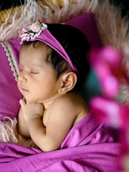 A beautiful side profile of a sleeping newborn, with a soft focus on a flower in the foreground to add depth.