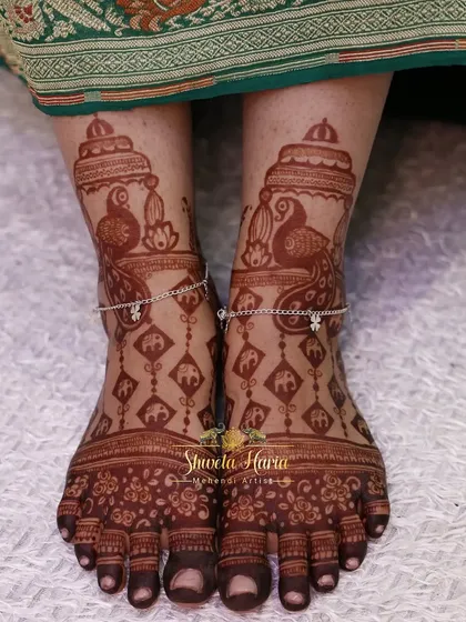 The beautiful final stain of a bridal foot design, showcasing peacock and baby elephant motifs with delicate payal-like patterns.