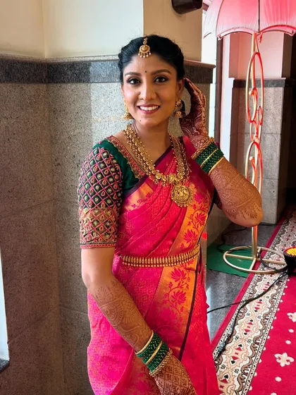 A full-length shot of my lovely client, showcasing her complete look for her pre-wedding ceremony. She is wearing a beautiful pink and green saree, complemented by my simple makeup and rental jewelry.