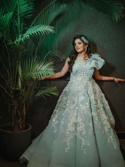 A full-length shot of the bride against a dark background. Her powder blue gown and radiant makeup create a stunning contrast.
