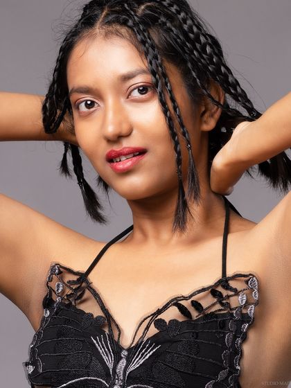 A close-up beauty shot, focusing on the model's makeup and braids.