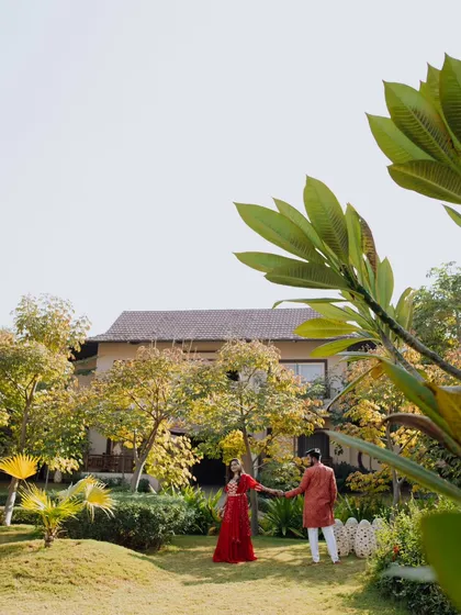 A wide-angle shot capturing the couple in the beautiful landscaped gardens of a resort, showcasing the serene and luxurious setting of their pre-wedding shoot.