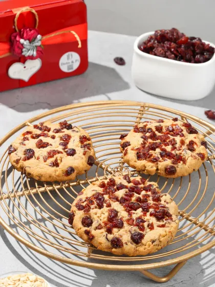 Cranberry cookies styled on a golden wire rack with a festive gift box in the background. This setup is ideal for seasonal promotions and holiday-themed product listings.