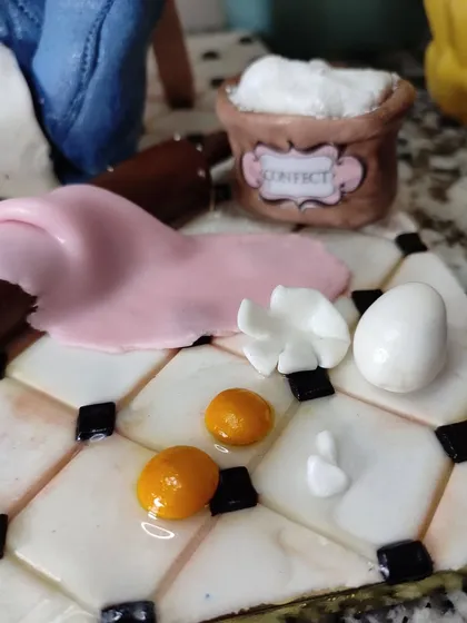 A close-up of the baker's life cake, showing the tiny edible eggs, flour sack, and rolling pin.