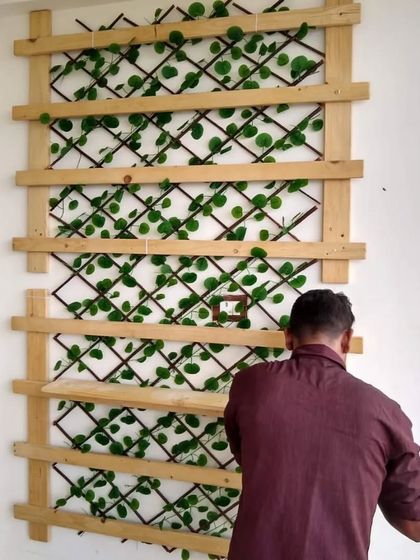 A glimpse of my team member at work, installing a custom pinewood and artificial leaf trellis. This is part of the process of building a beautiful vertical garden wall.