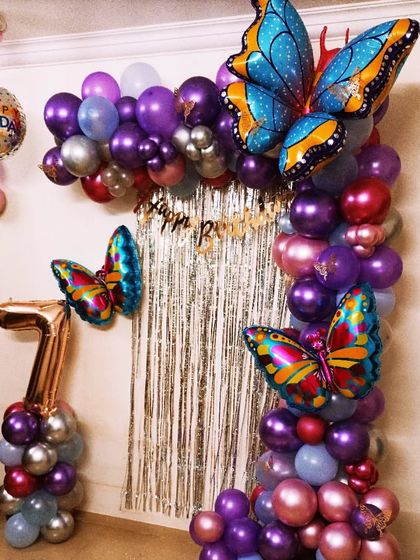 A beautiful butterfly-themed balloon arrangement for a 7th birthday. The large, colorful foil butterflies are the stars of this setup, perfect for a home celebration.