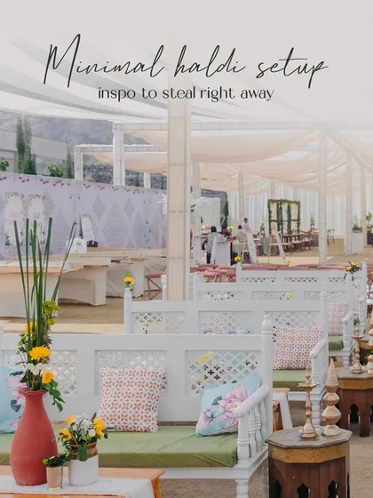 A chic and minimal Haldi seating area with white wooden benches, patterned cushions, and simple floral arrangements. This shows my ability to create understated yet beautiful event designs.