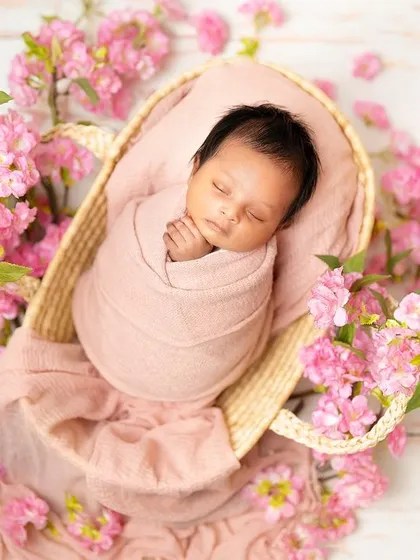 Another angle of this beautiful floral setup, showing the baby peacefully asleep in a woven basket on a bed of pink flowers. This highlights the artistry of my prop styling.