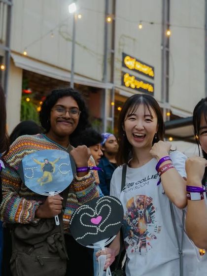Happy fans proudly showing off their handmade signs and official wristbands. We focus on the entire fan journey, from ticketing to the final encore, to build a strong and engaged community.
