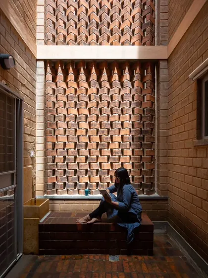 In this quiet courtyard nook, an intricately patterned brick screen, or jali, filters sunlight beautifully. This detail is more than just decoration; it’s a passive cooling strategy that allows for ventilation while providing privacy, demonstrating how traditional craftsmanship can create both comfort and art.