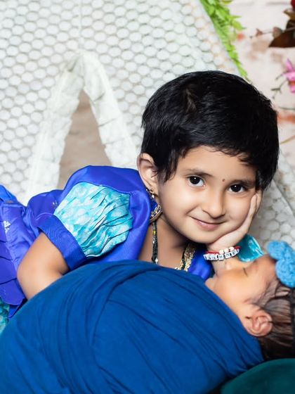 A sweet moment between two sisters, with the younger one giving the older one a kiss on the cheek.