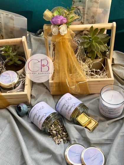 A closer look at our wedding invitation hampers. This set includes a succulent, jars of mixed seeds and handmade chocolates, and a beautiful handmade candle, all in a decorated pinewood basket.