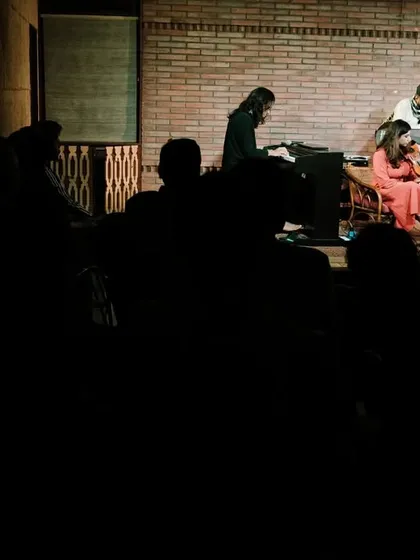 A wide shot showing the silhouetted audience watching REFUGE perform at the Jazz Festival. This view emphasizes the intimate connection between the performers and listeners at Koota.