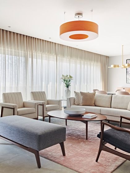 The living room of the Maximum City Duplex is a blend of soft pastels and neutral tones. Floor-to-ceiling sheer curtains diffuse the natural light, creating a bright and airy ambiance.