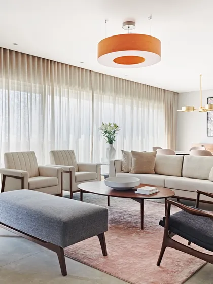 This living room in the Maximum City Residence uses a neutral and pastel color palette to create a bright, airy feel. Floor-to-ceiling sheer curtains diffuse natural light, enhancing the sense of calm and spaciousness.
