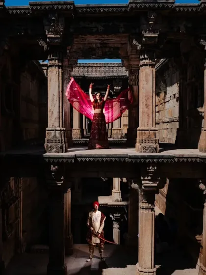 A multi-level portrait within the stepwell, showing the bride on an upper level and the groom below. This composition highlights the grand scale of the location while telling a story of connection across spaces.