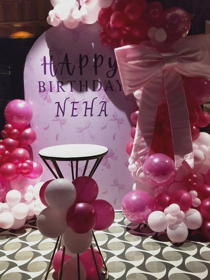 A full view of the pretty pink bow-themed birthday setup. The arrangement includes a small table for the cake, ensuring the entire display is both beautiful and functional for the celebration.
