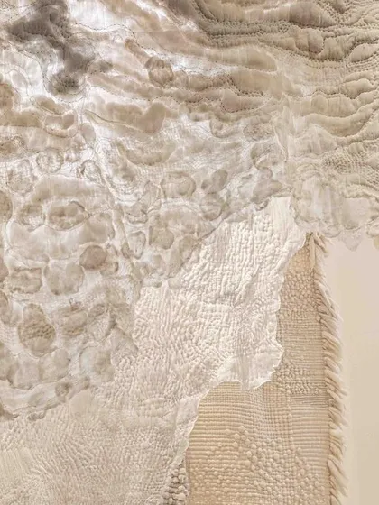 An overhead view of the 'Sleep Sense' textile installation. The piece looks like a collection of floating clouds or soft, geological formations, creating a dream-like atmosphere.