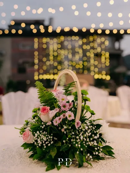 A beautiful centerpiece in a wicker basket, with the soft bokeh of fairy lights in the background. This creates a warm and rustic-chic vibe.