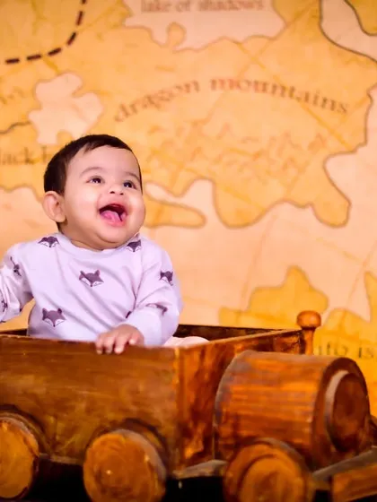A happy baby in a wooden cart against a pirate map background, ready for an adventure.