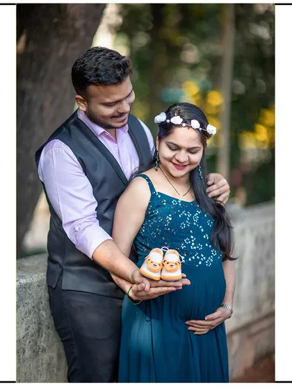 A smiling couple holding up baby shoes together, a classic and heartwarming shot for any maternity session.