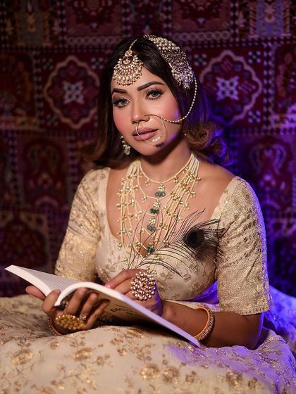 A studious and royal pose, this look features a layered pearl and emerald necklace over an ivory lehenga.