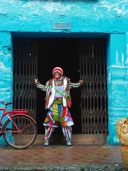 Framing the extraordinary within the ordinary. The model, dressed in a riot of color, stands within the stark entrance of a local ice factory, creating a powerful visual contrast for this experimental fashion story.