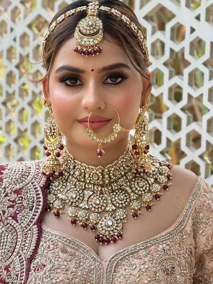 A close-up portrait of a bride with flawless airbrush makeup. The focus is on her bold, beautiful eyes and the intricate details of her kundan jewelry.