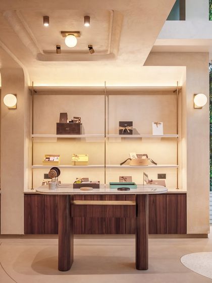 We believe furniture should be integral to the architecture. This custom-designed table at Entisi features a marble top and fluted wooden legs, serving as a functional display while echoing the store's language of clean lines and premium materials.
