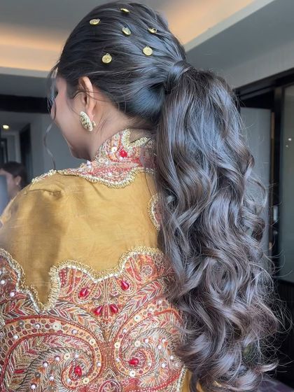 A close-up of the coin-adorned ponytail, showing the detail of the accessories and the texture of the hair.