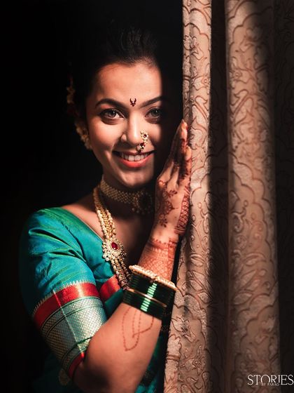 A beautiful bridal portrait of a bride peeking out from behind a curtain. Her bright smile and sparkling eyes create a sense of playful charm and happiness.
