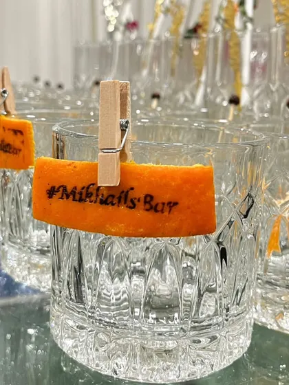 A close-up of our custom heat-stamped garnish. We can burn a hashtag, logo, or initials onto citrus peels, adding a unique and highly personalized branding element to your cocktails.