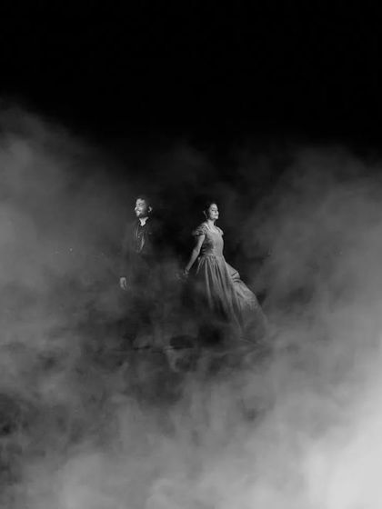 A dramatic black and white photo where the couple emerges from a cloud of smoke. This technique creates a mysterious and cinematic feel, like a scene from a classic film noir.