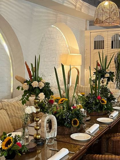 The tablescape for the "Bearly Wait" baby shower. We used rustic wooden tables and filled them with vibrant floral arrangements, including bright yellow sunflowers, to create a cheerful and sunny atmosphere.