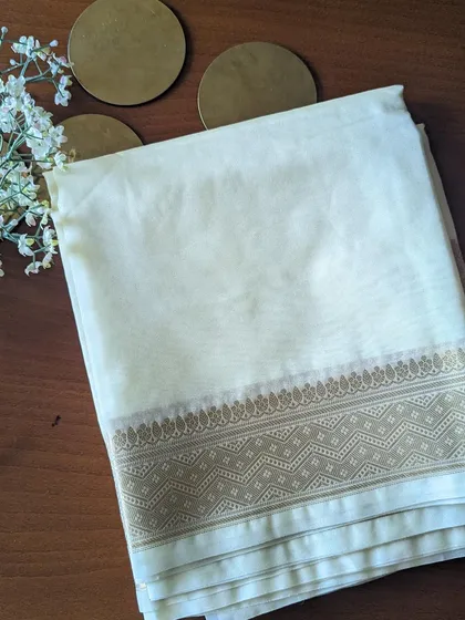 The off-white Kora Organza saree is a vision of grace. The fabric is sheer and lightweight, with a beautiful antique gold border.