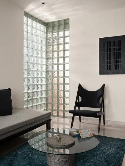 We brought back glass blocks, a material from the 1980s, to solve a lighting problem and create a stunning feature. This corner in the multipurpose room shares a glass block wall with the living area, seamlessly connecting the spaces with diffused, natural light.
