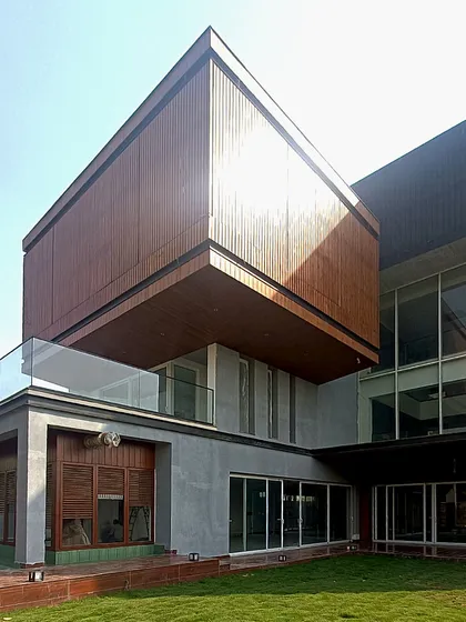 A detail of the Lakewood Residence facade, where a cantilevered wooden-clad volume creates a dramatic overhang, providing shade and adding depth to the building's exterior.