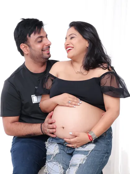Pure joy and laughter. This candid shot of a couple in casual wear captures the fun and excitement of waiting for their baby.