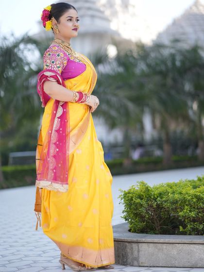 A graceful pose in a yellow Nauvari saree, showing how the traditional attire looks against a beautiful outdoor backdrop.