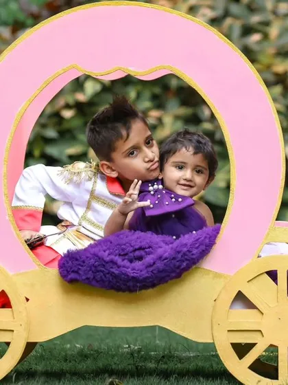 A sweet moment between siblings in a whimsical carriage prop during an outdoor photoshoot.