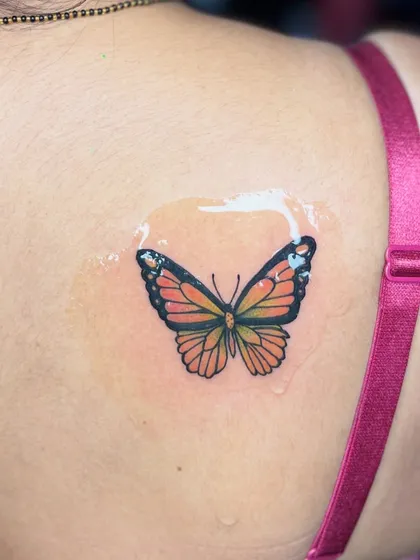 A small, colorful butterfly tattoo on the shoulder. Even small pieces can have a big impact with the right colors and placement.