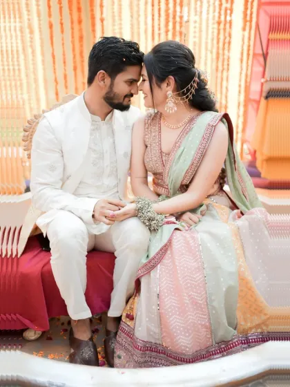 An intimate close up of the couple during their Haldi. Their coordinated white outfits contrast beautifully with the yellow decor, and their connection is palpable.