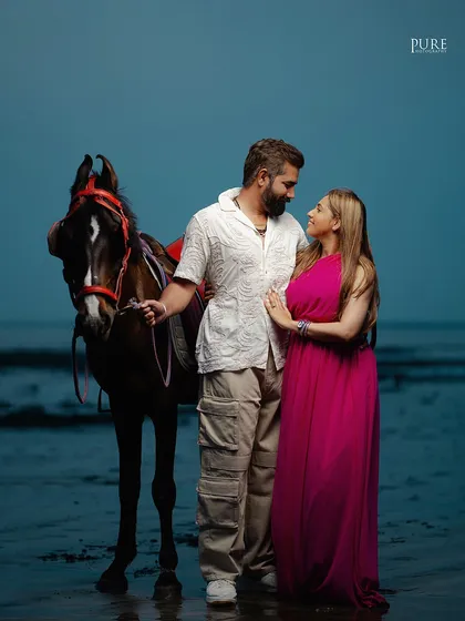 Adding a unique element to their beach photoshoot, Nishant and Jaspal pose with a horse by the water's edge. This creates a powerful and almost mythical image.