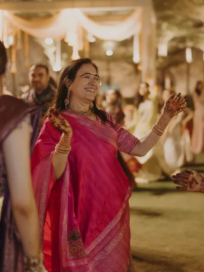 The mother of the bride enjoying the sangeet night. Her bright pink saree stands out, showcasing her vibrant personality and the celebratory spirit of the event.
